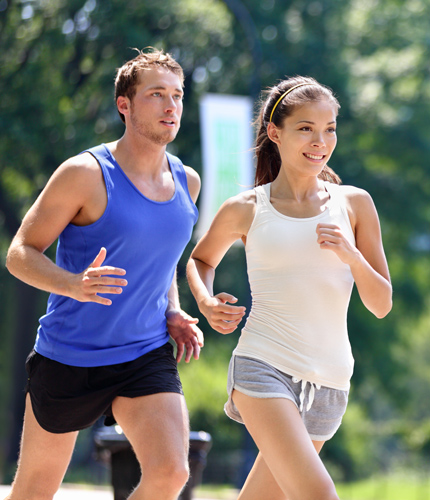 Pareja corre con ropa deportiva, hombre en camiseta azul, mujer en top blanco, fondo de parque.